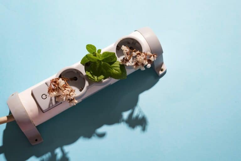 electronic cable plug with green mint and flowers on blue background. Friendly green living. Earth