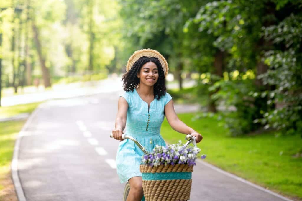 Young black girl going for ride on bike at beautiful green park in summer